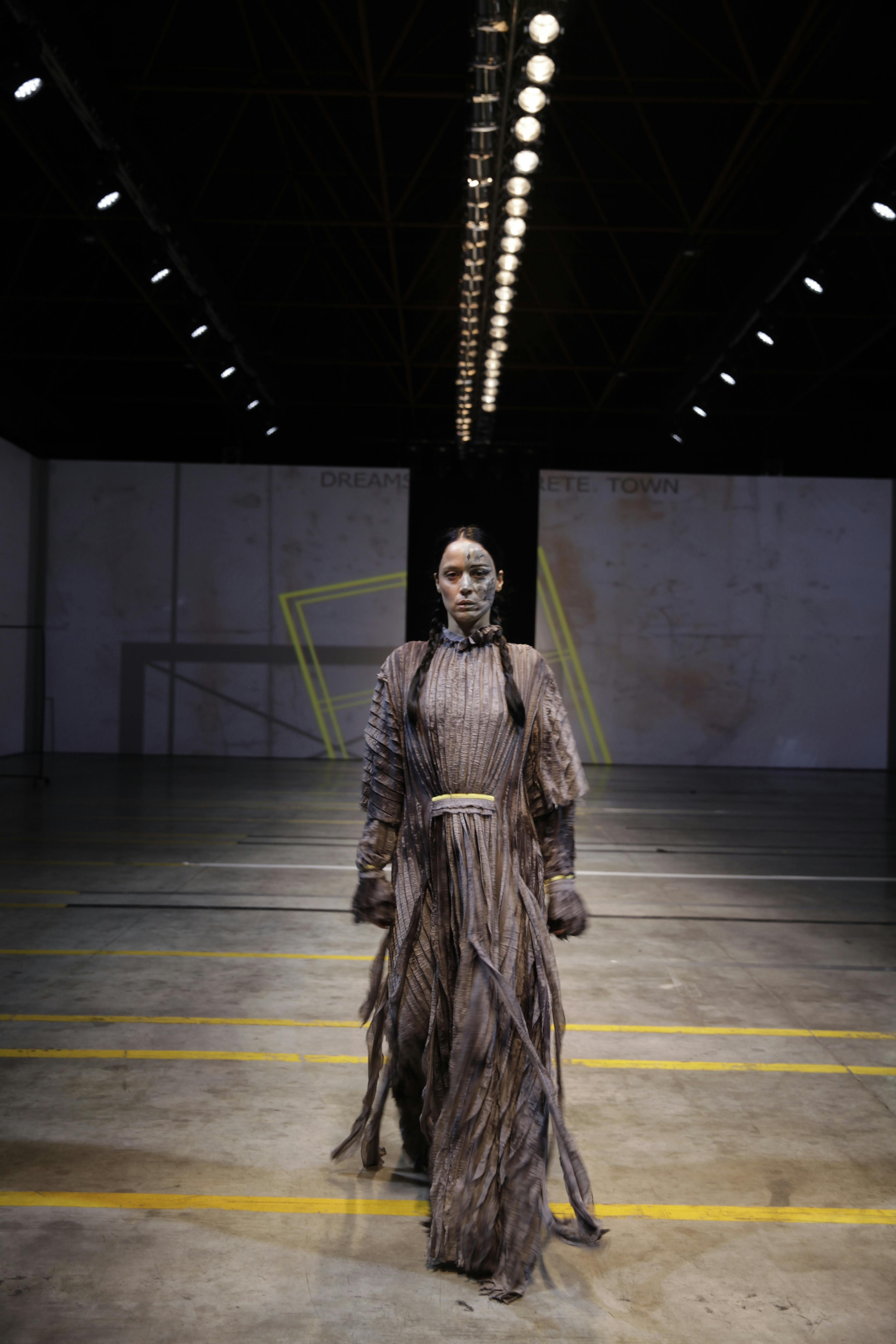 Spotlit runway walk standing in for the official fashion machine that no longer owns the season