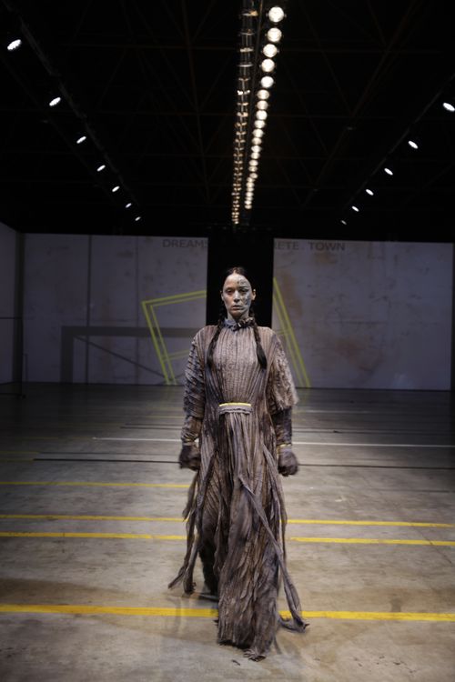 Free Model in a dramatic dress striding down an indoor runway, spotlight focuses intensity. Stock Photo