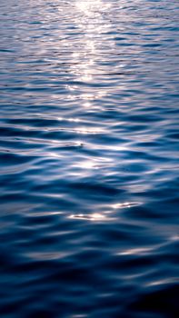 Serene ocean waves reflecting sunlight at twilight, creating a tranquil nature scene.
