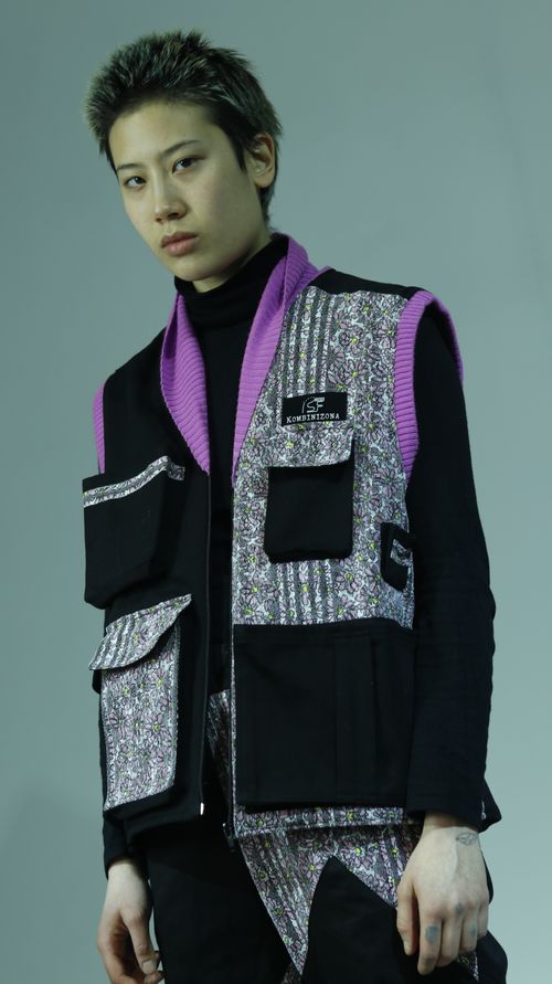 Free A trendy young adult poses confidently in a studio, showcasing modern fashion with a colorful layered outfit. Stock Photo