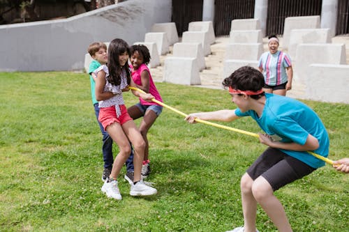 Free Children Playing Tug of War on Grass Field  Stock Photo