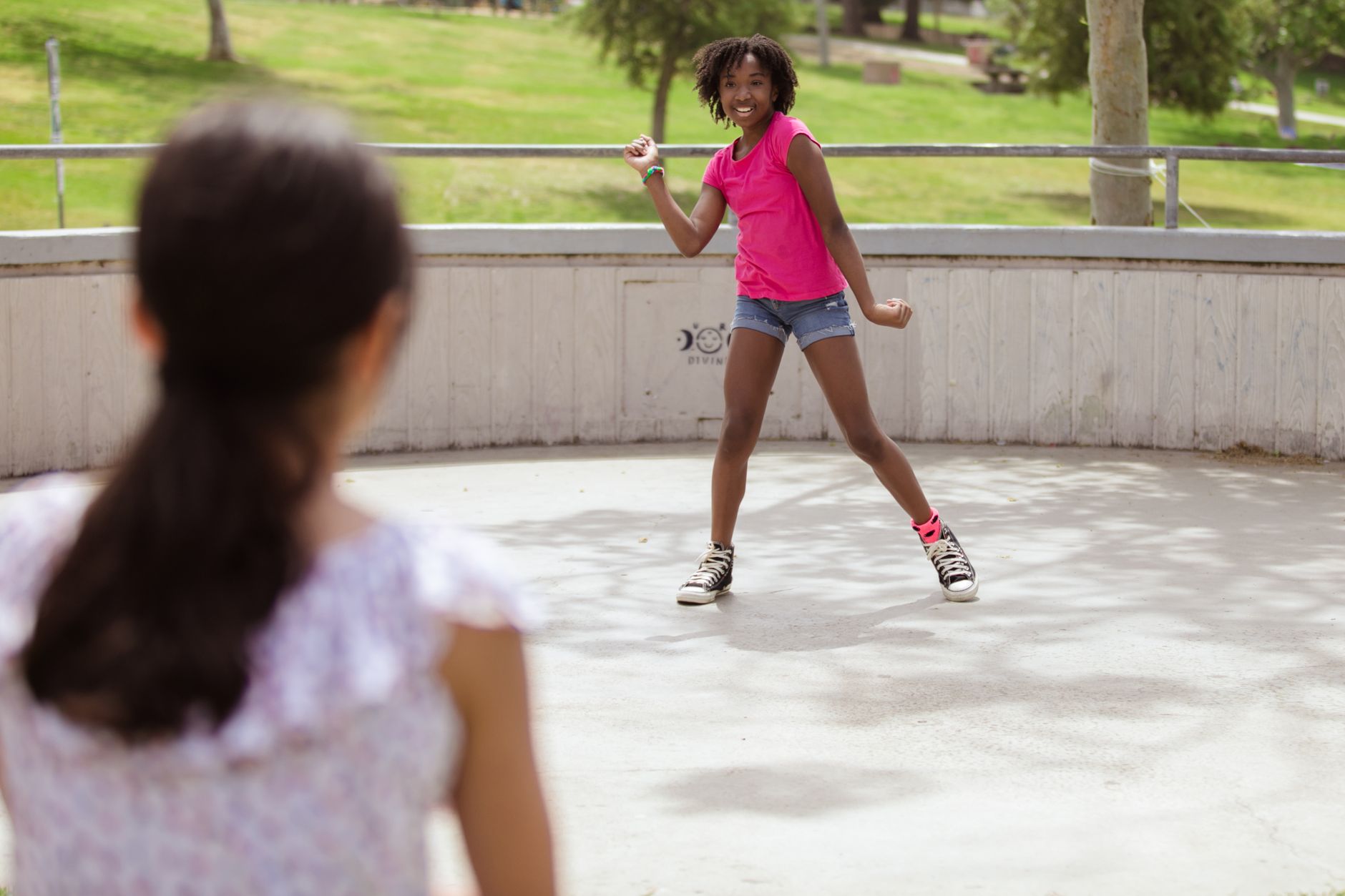 A lively child dances outdoors in a sunny park setting, exuding joy and fun.