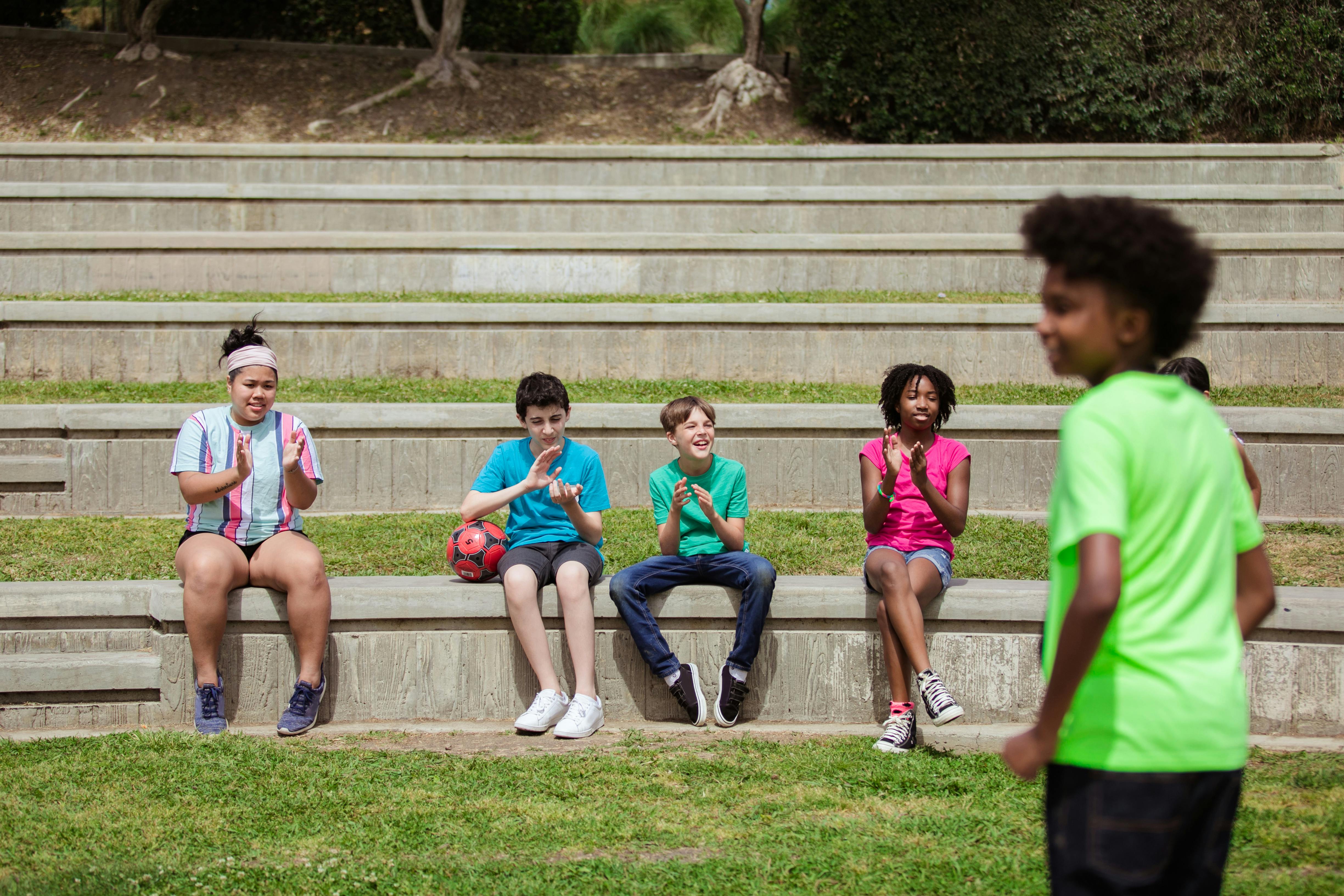 Free Group of children sitting and clapping at a soccer game in an outdoor amphitheater. Stock Photo