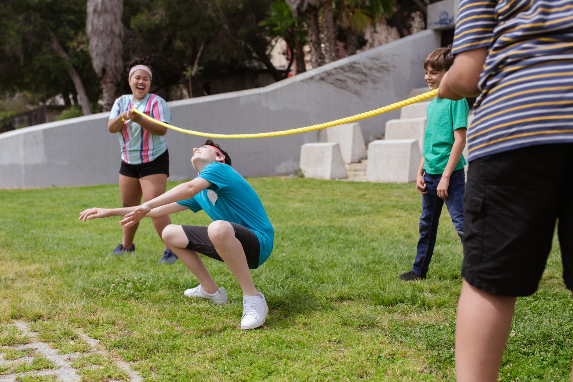Group of children enjoying a limbo game outdoors on a sunny day in the park.