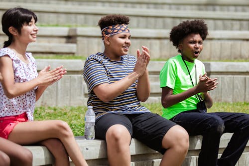 A Group of Kids Sitting on a Concrete Bench while Clapping Hands