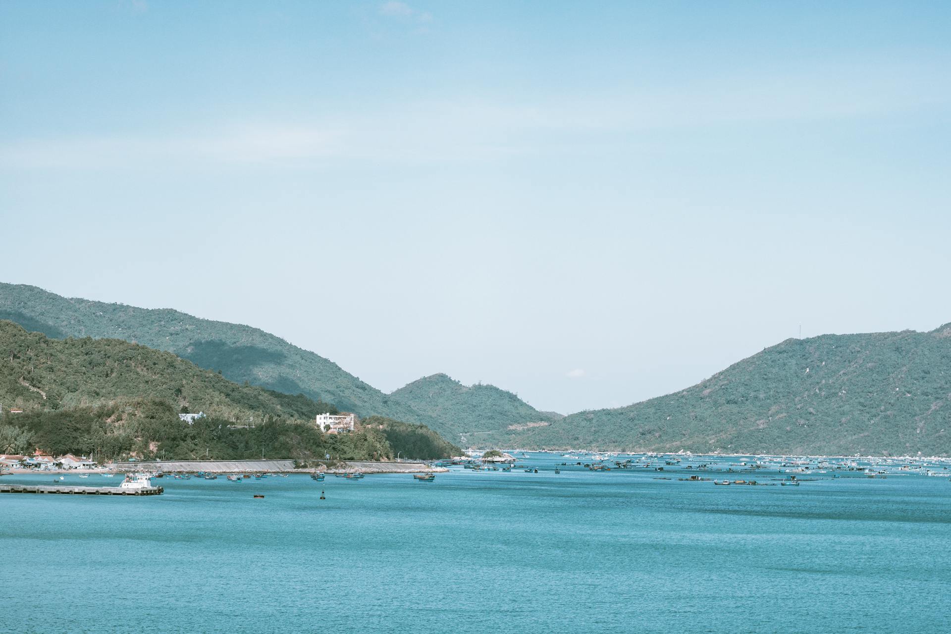 Idyllic coastal scene in Vietnam with clear blue waters and lush green hills under a sunny sky.