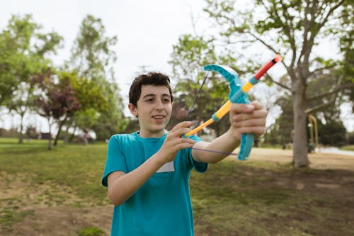 A Boy in a Blue Shirt Holding a Toy Bow and Arrow