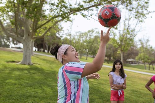Free Children joyfully playing with a football in a sunny park during summer camp. Stock Photo