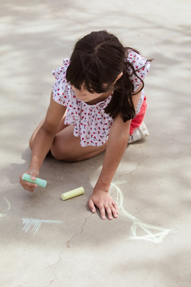 A Girl Drawing On The Floor Using A Chalk