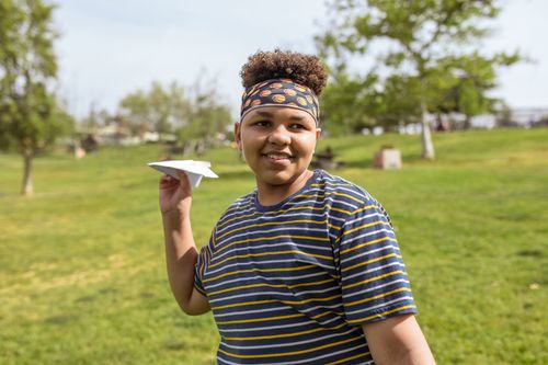 Free Cheerful child with paper airplane enjoying sunny day in the park. Stock Photo