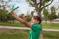 Close-Up Shot of a Boy using a Slingshot while Smiling