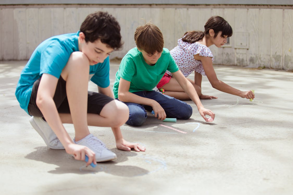 Three Kids Drawing on the Floor using Chalks · Free Stock Photo