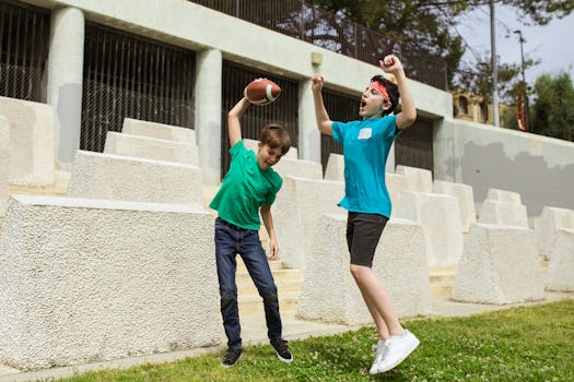Two boys excitedly play with an american football outdoors, showcasing sportsmanship and energy.