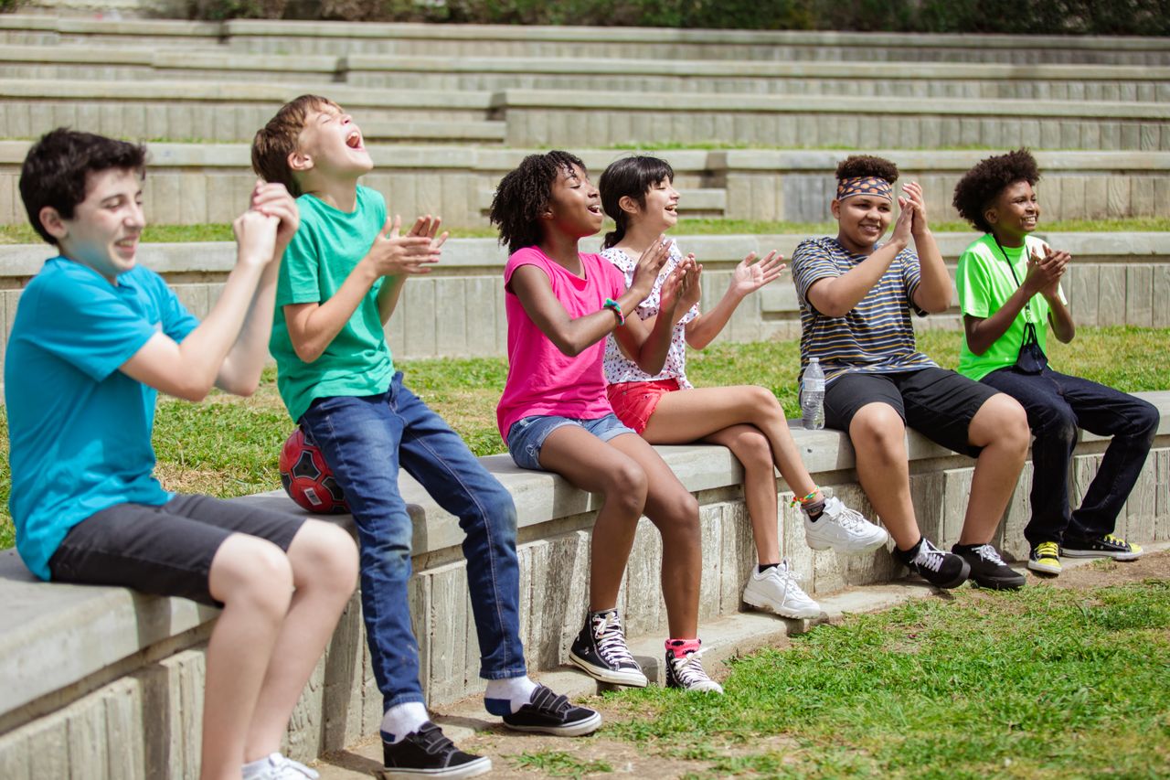 a group of children joyfully clapping and cheering together while sitt