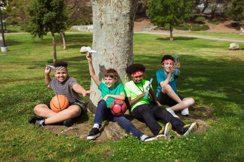 Free A group of kids having fun with balls and paper planes in a sunny park setting. Stock Photo