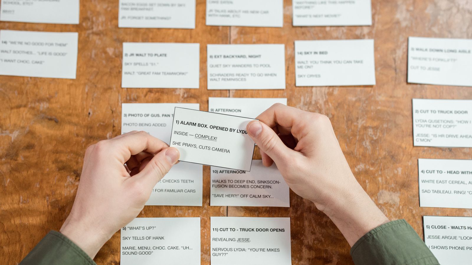 Hands arranging index cards with handwritten notes on a desk