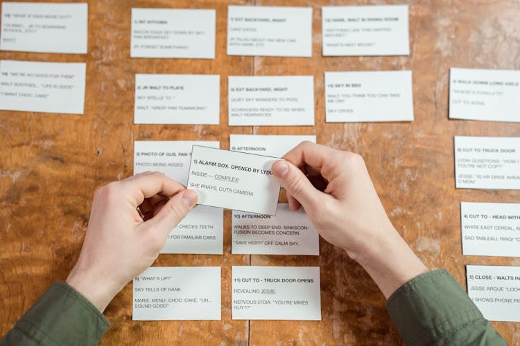 Close-up Of Person Sitting At Desk Studying With Cards