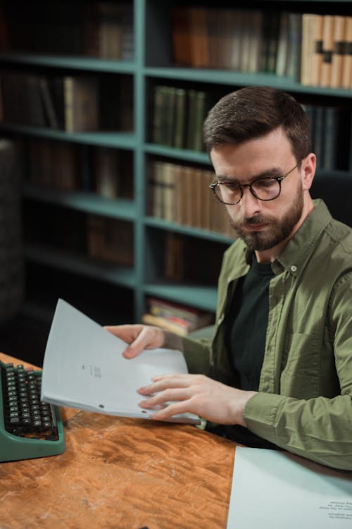 Free Close-Up Shot of a Man with Eyeglasses Holding Papers Stock Photo