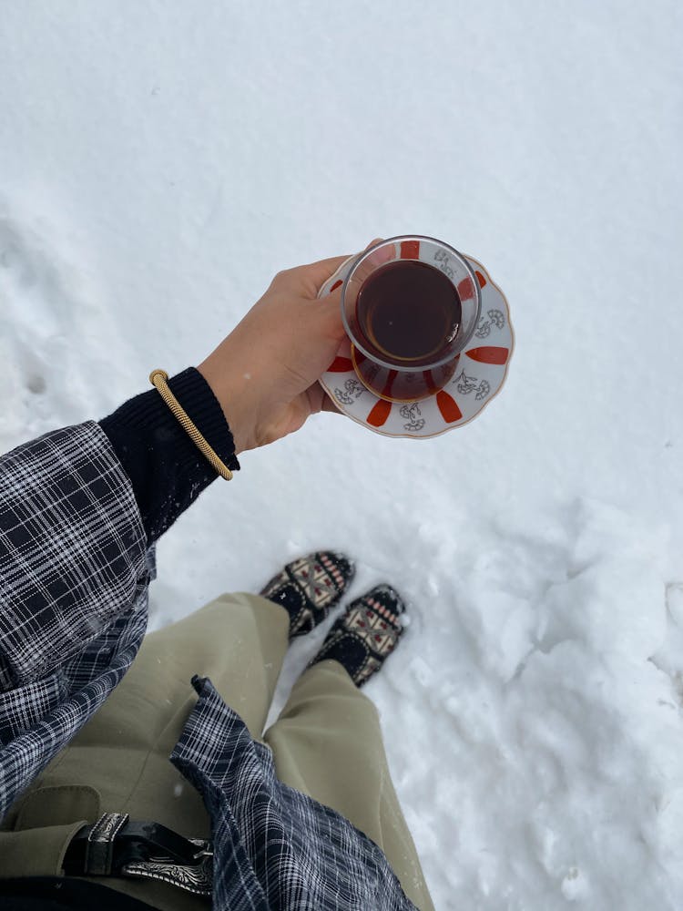 Crop Person On Snow With Cup Of Hot Tea