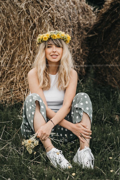 Smiling woman in wreath of flower sitting on grass