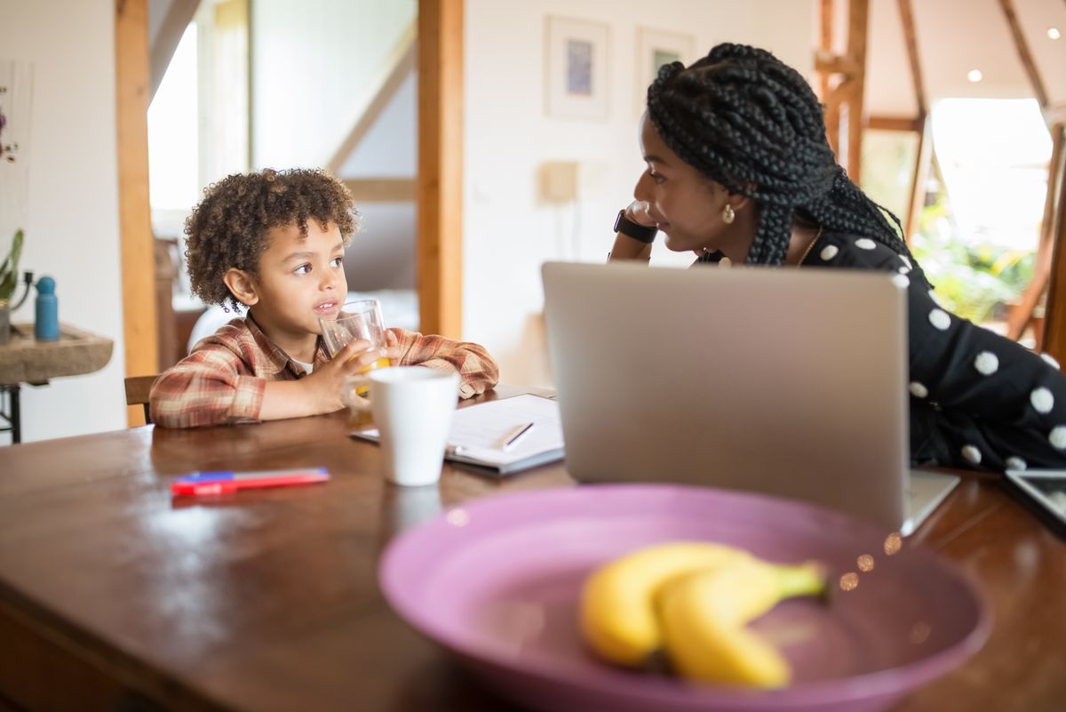 Mother and son talking at a kitchen table at home