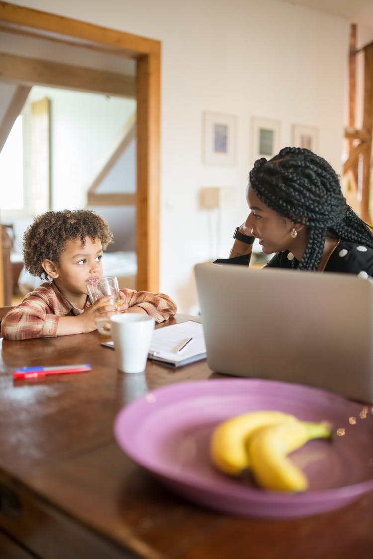 Black Mother And Little Child Sitting At Table At Home