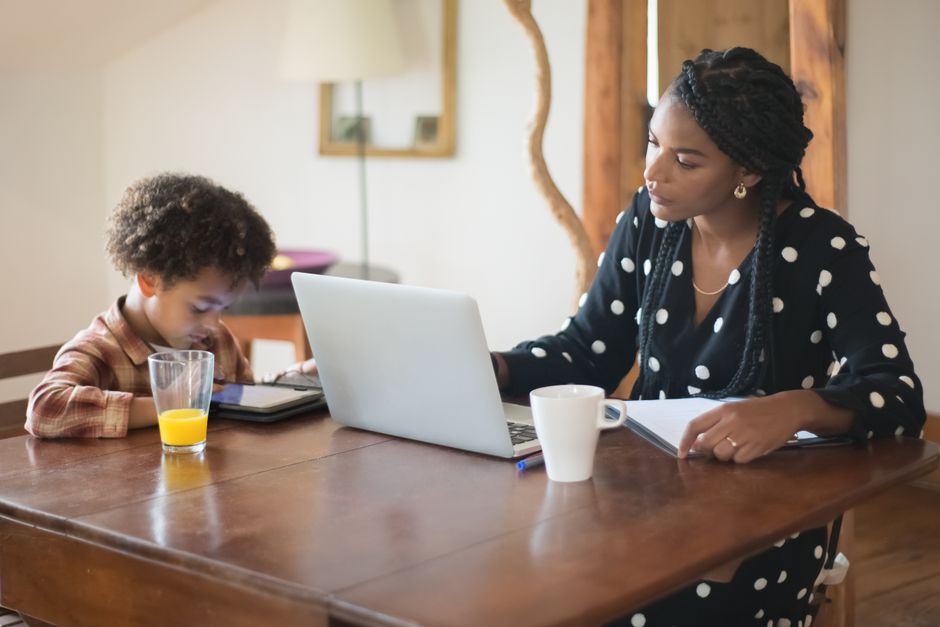 Mother and son using a laptop and tablet at home, exploring technology together.