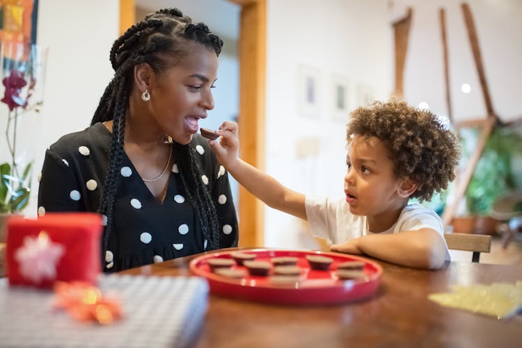 Black Mother And Child Sitting At Table Eating Cookies