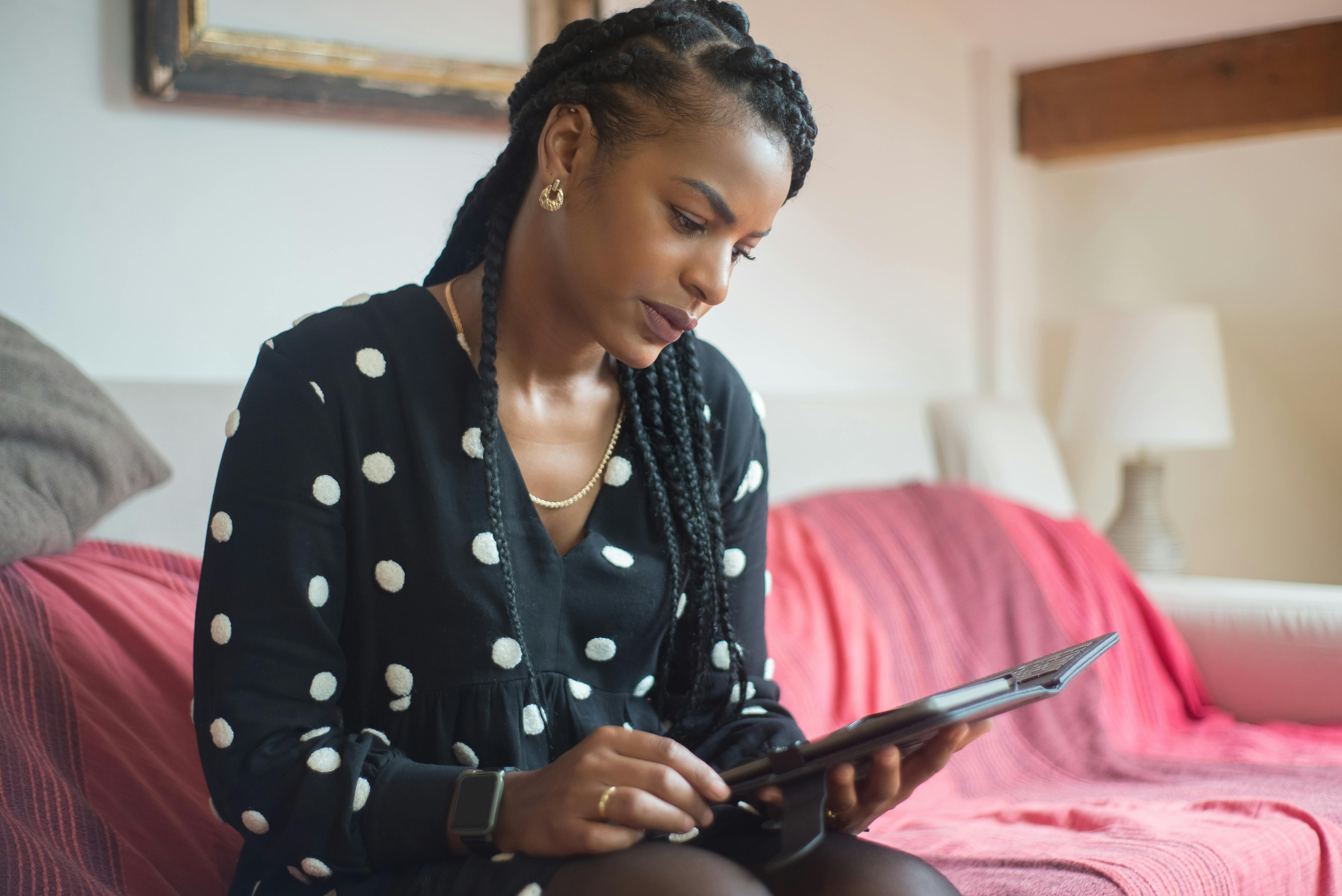 African American woman using a tablet on a comfortable couch at home.