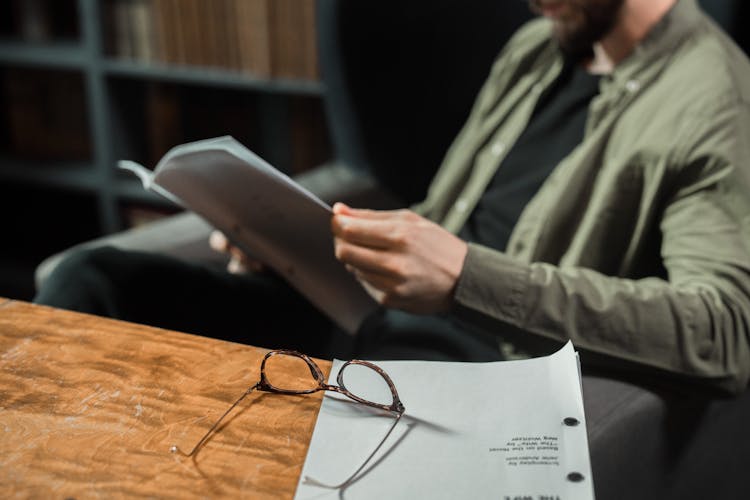 Man Sitting In Chair Reading Paperwork