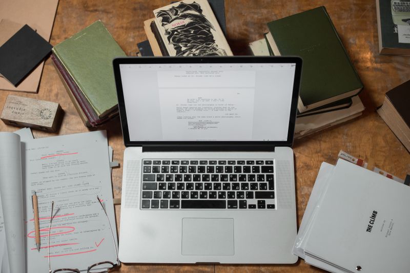 Portátil rodeado de libros y guiones
