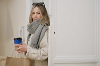 Photo of a Woman with a Gray Scarf Holding a Cup of Coffee