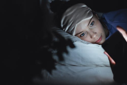 Free Woman Lying on bed Using a Smartphone Stock Photo