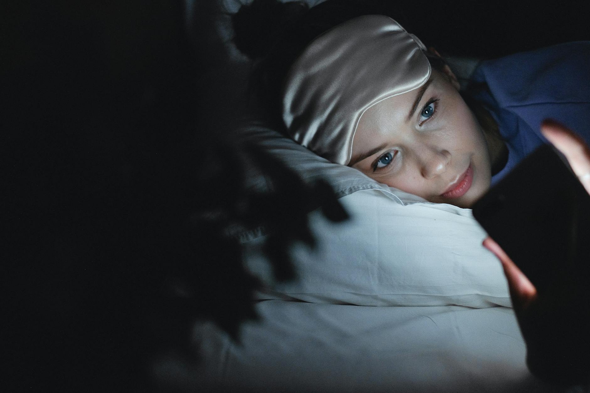 person sleeping peacefully in a dark bedroom with white bedding and blackout curtains