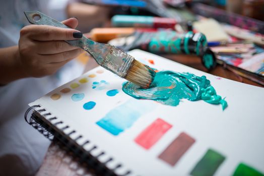 Artist mixing vibrant paints on a sketchbook using a brush. Perfect for creative arts promotion.