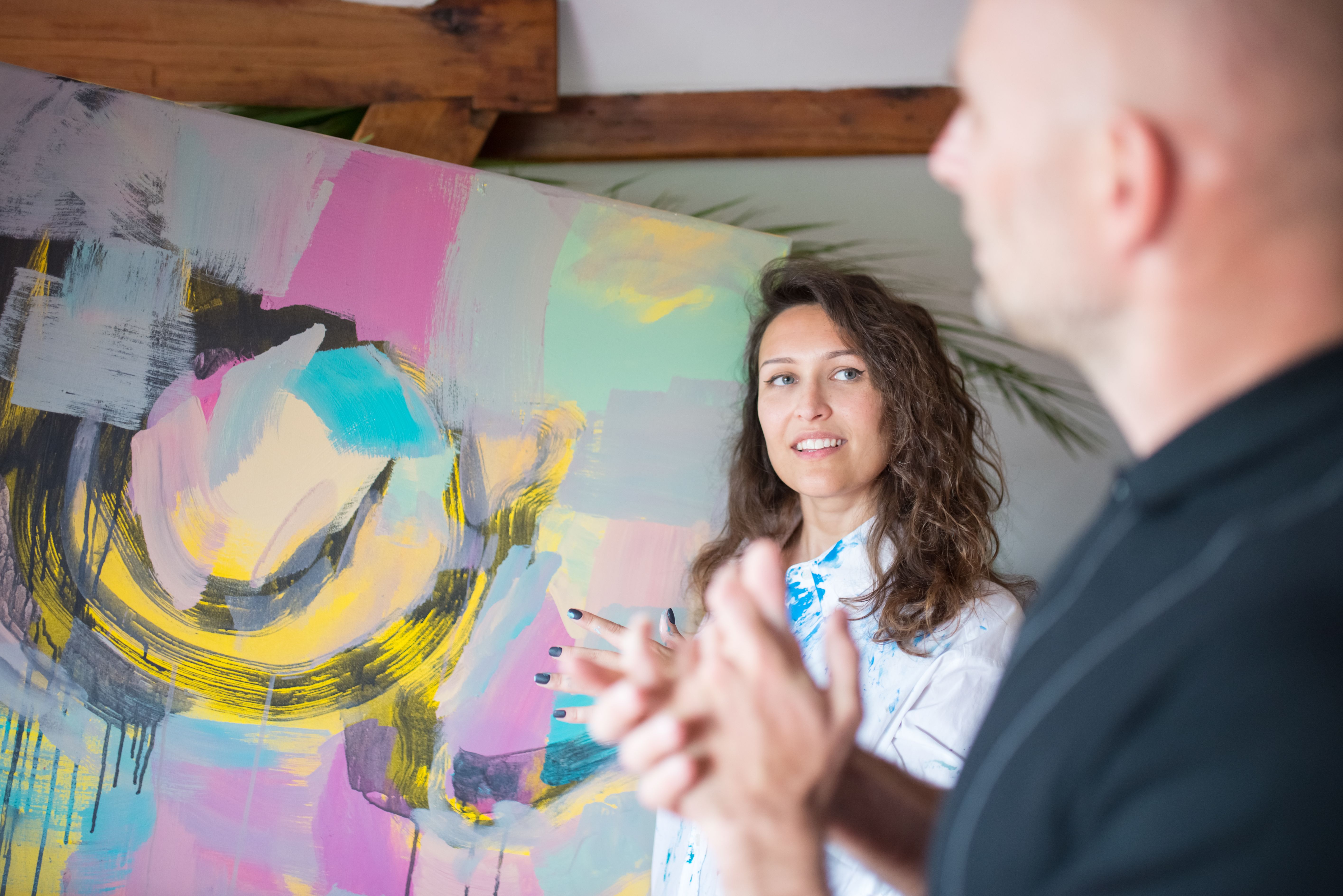 [ColoSach]-two-adults-discuss-vibrant-abstract-painting-in-a-studio.-creative-interaction-captured.