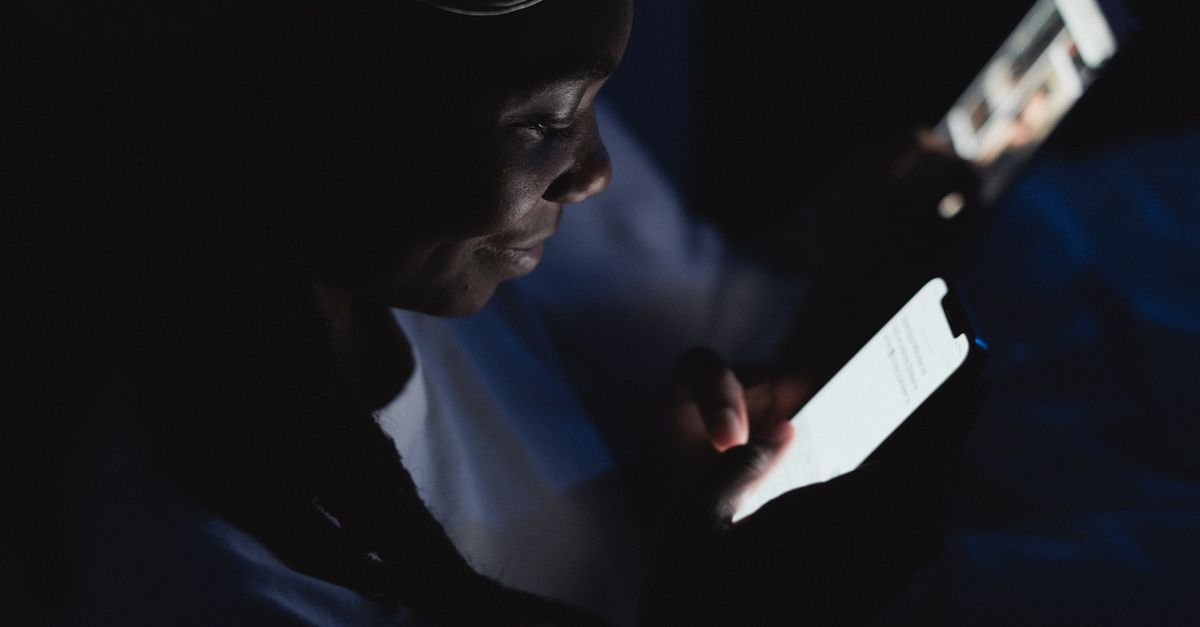 A serene digital art depiction of a person meditating with a smartphone glowing in a dark room, surrounded by ethereal light