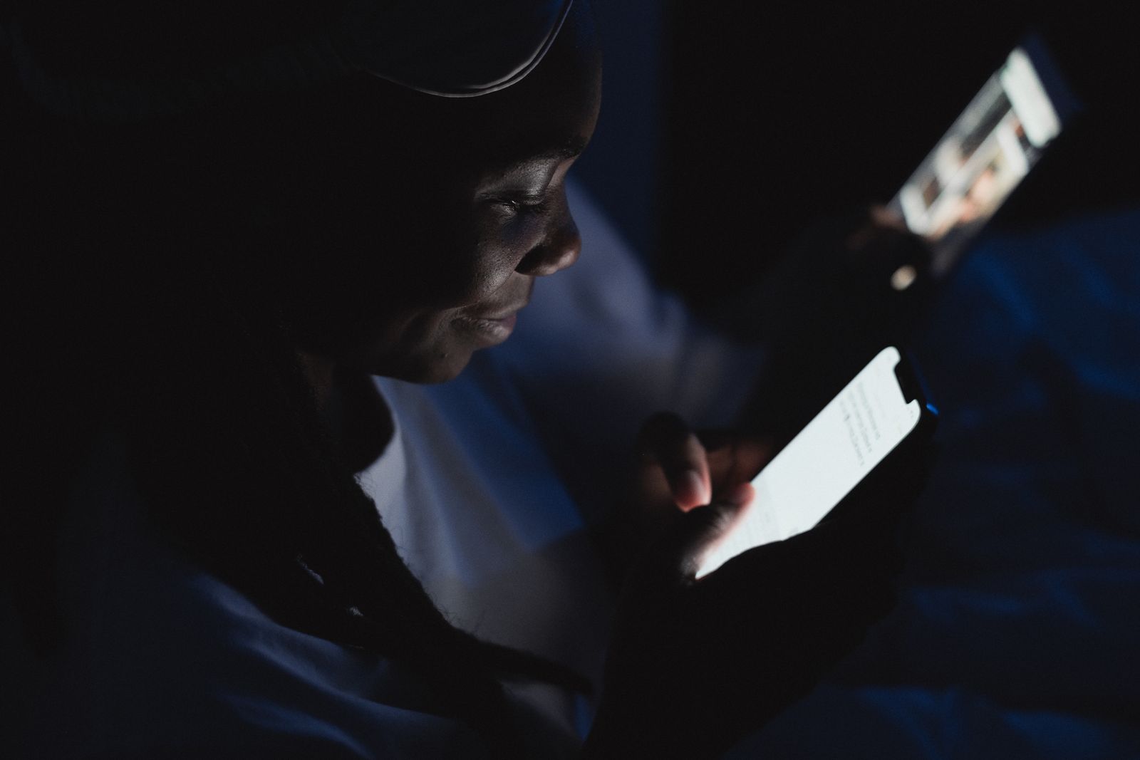 Personne lisant sur l'écran lumineux d'un smartphone dans la pénombre