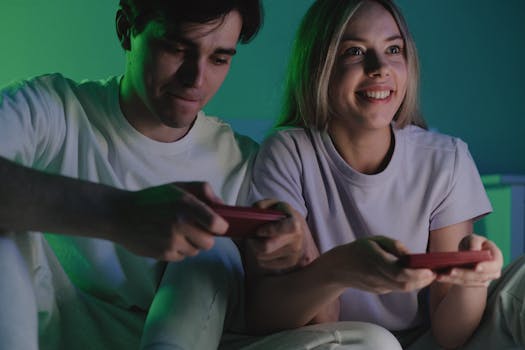 A happy couple sits indoors playing video games with controllers, enjoying a fun and relaxed time.