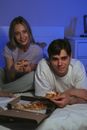 A Couple Eating Pizza Wile on the Bed