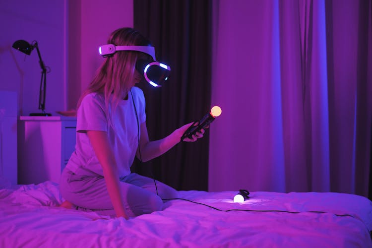 Woman Wearing A Virtual Reality Googles Kneeling On A Bed