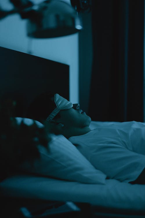 Free Man Wearing a Sleep Mask Lying on Bed  Stock Photo