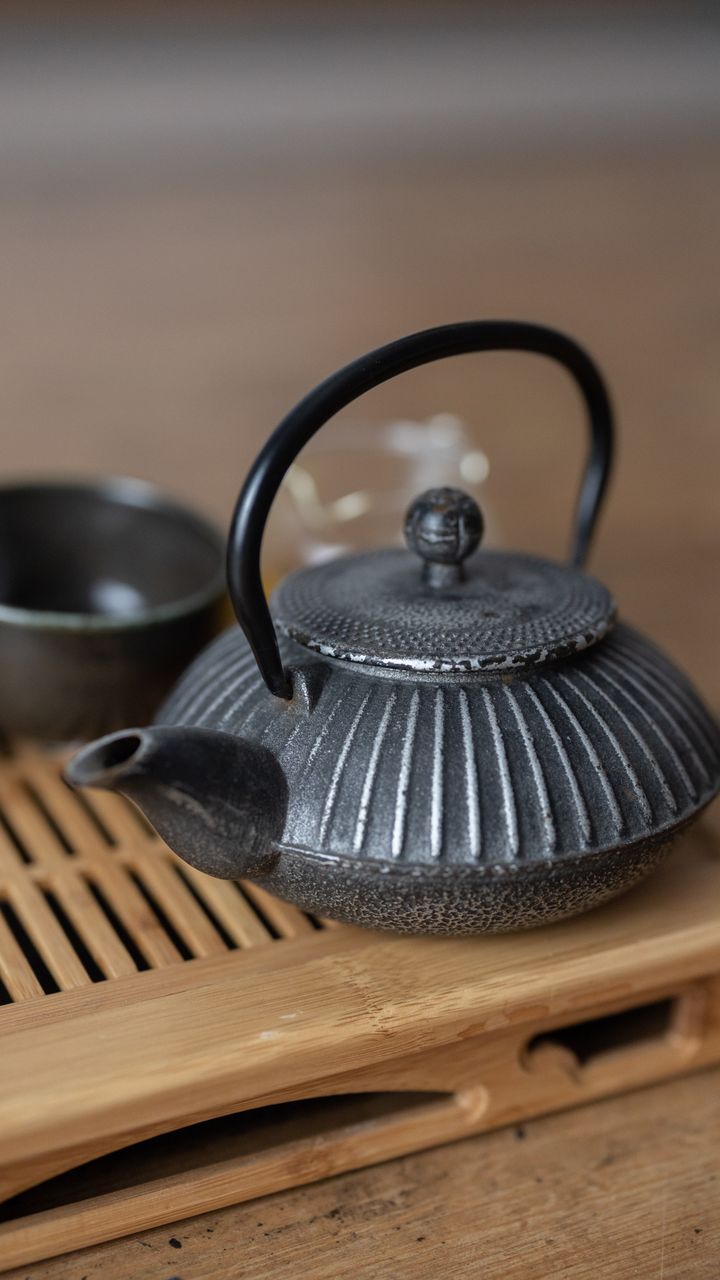 round galvanized metal trivet sitting on a wooden coffee bar counter next to a coffee maker