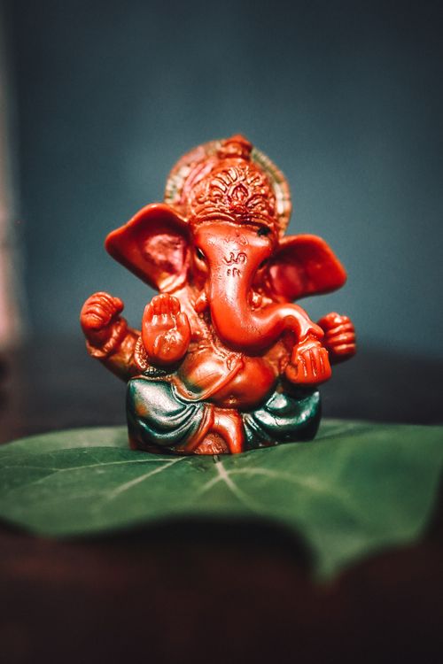 Free Close-up of a colorful Ganesha figurine on a green leaf, symbolizing spirituality and Hindu culture. Stock Photo