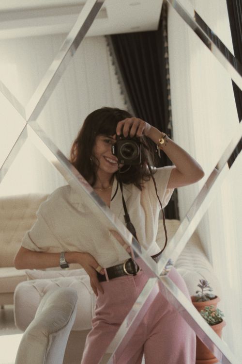 Free Stylish woman taking a selfie in a mirror with a DSLR camera indoors. Stock Photo