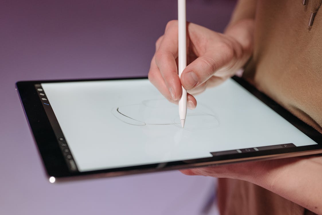 Free A Person using a Stylus Pen on a Tablet Stock Photo