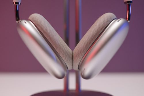 Free Close-up of sleek silver headphones on a stand, set against a purple background. Stock Photo