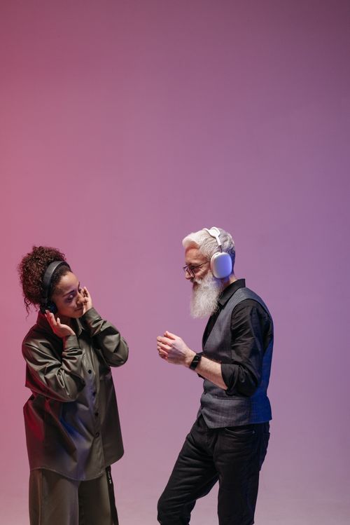 Free Two adults enjoying music with headphones in a colorful studio setting. Stock Photo