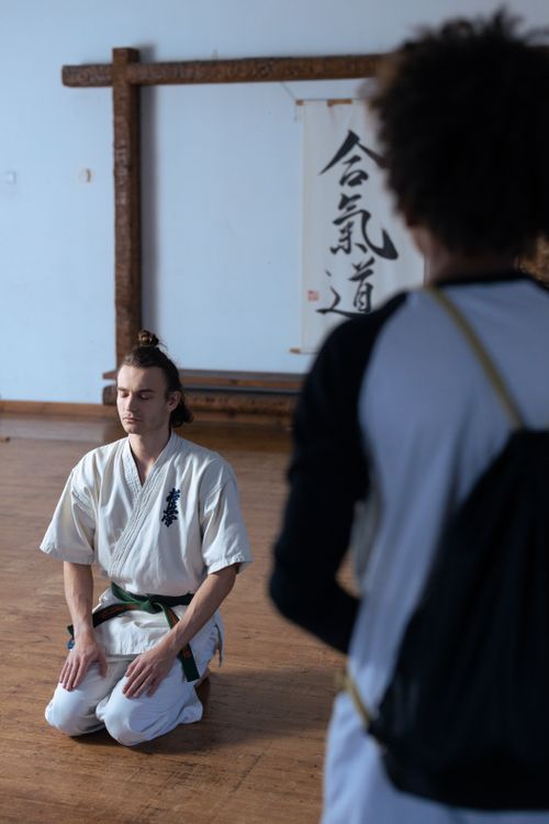 Free Martial artist kneeling and meditating inside a dojo, focusing on mindfulness and discipline. Stock Photo