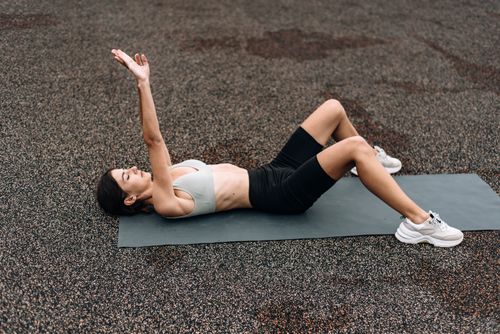Free Woman in activewear stretches on a yoga mat outdoors, promoting a healthy lifestyle. Stock Photo